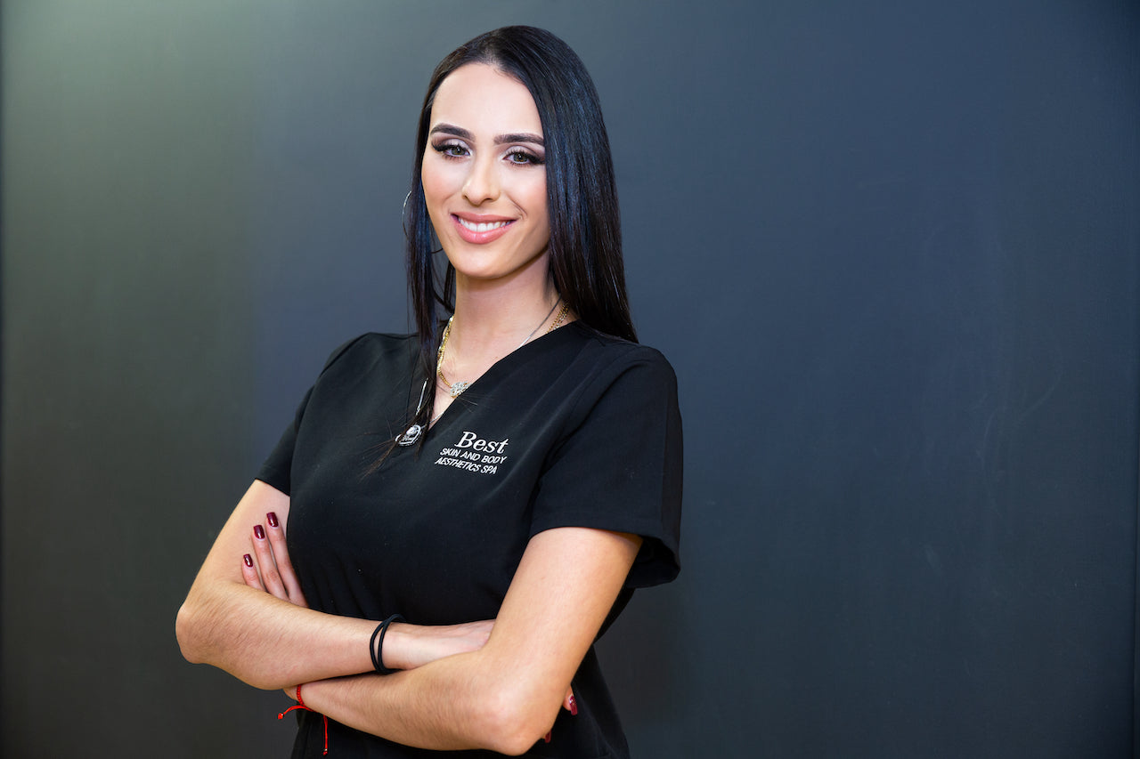 A woman in black scrubs posing with arms crossed.